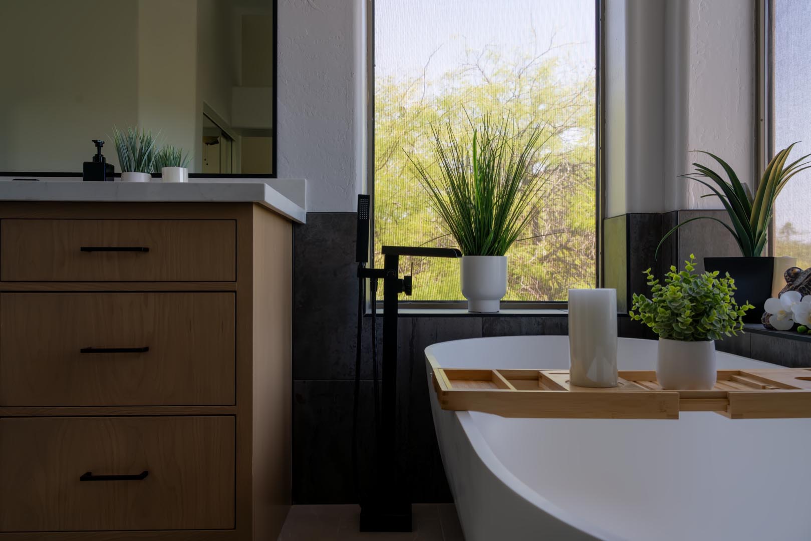 Freestanding soaking tub beside a white oak vanity in a remodeled bathroom