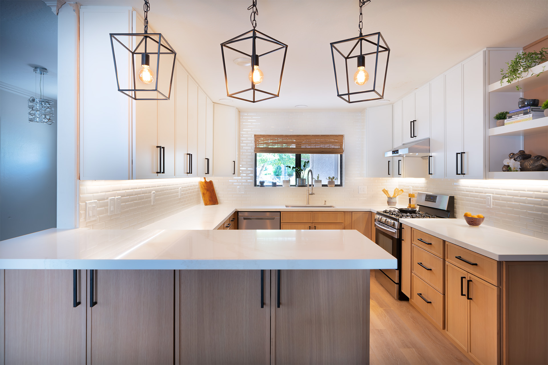 Open kitchen remodel with white cabinetry, lantern pendants and a quartz peninsula